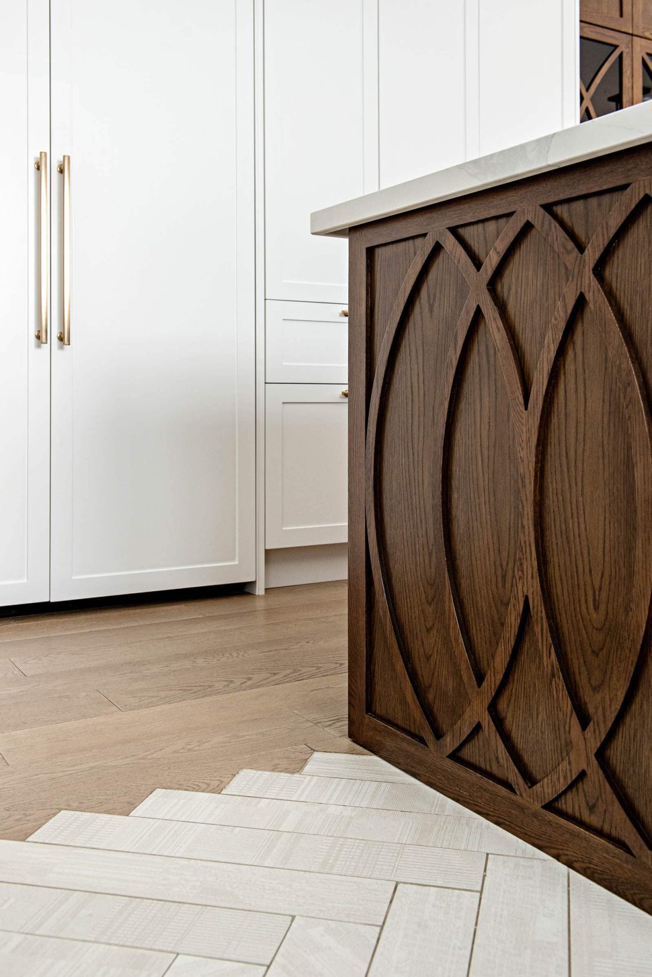 White kitchen cabinets with wood island and herringbone tile to wood transition details