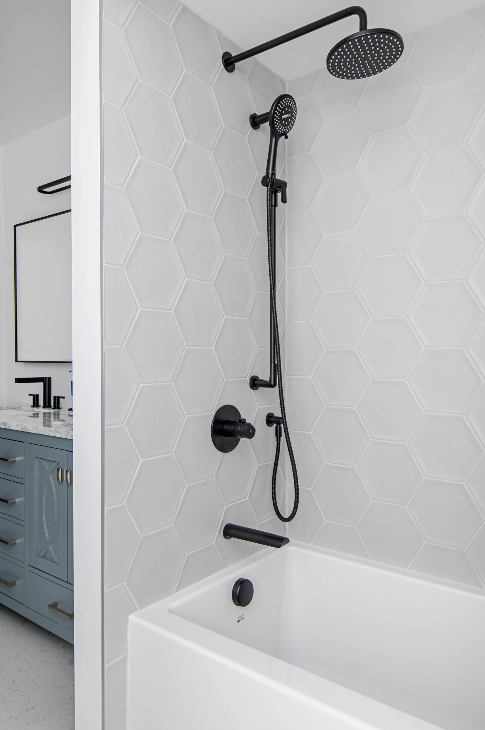 Image of Second Floor Bathroom shower tub combo renovation, with hexagon wall tiles and black plumbing fixtures.