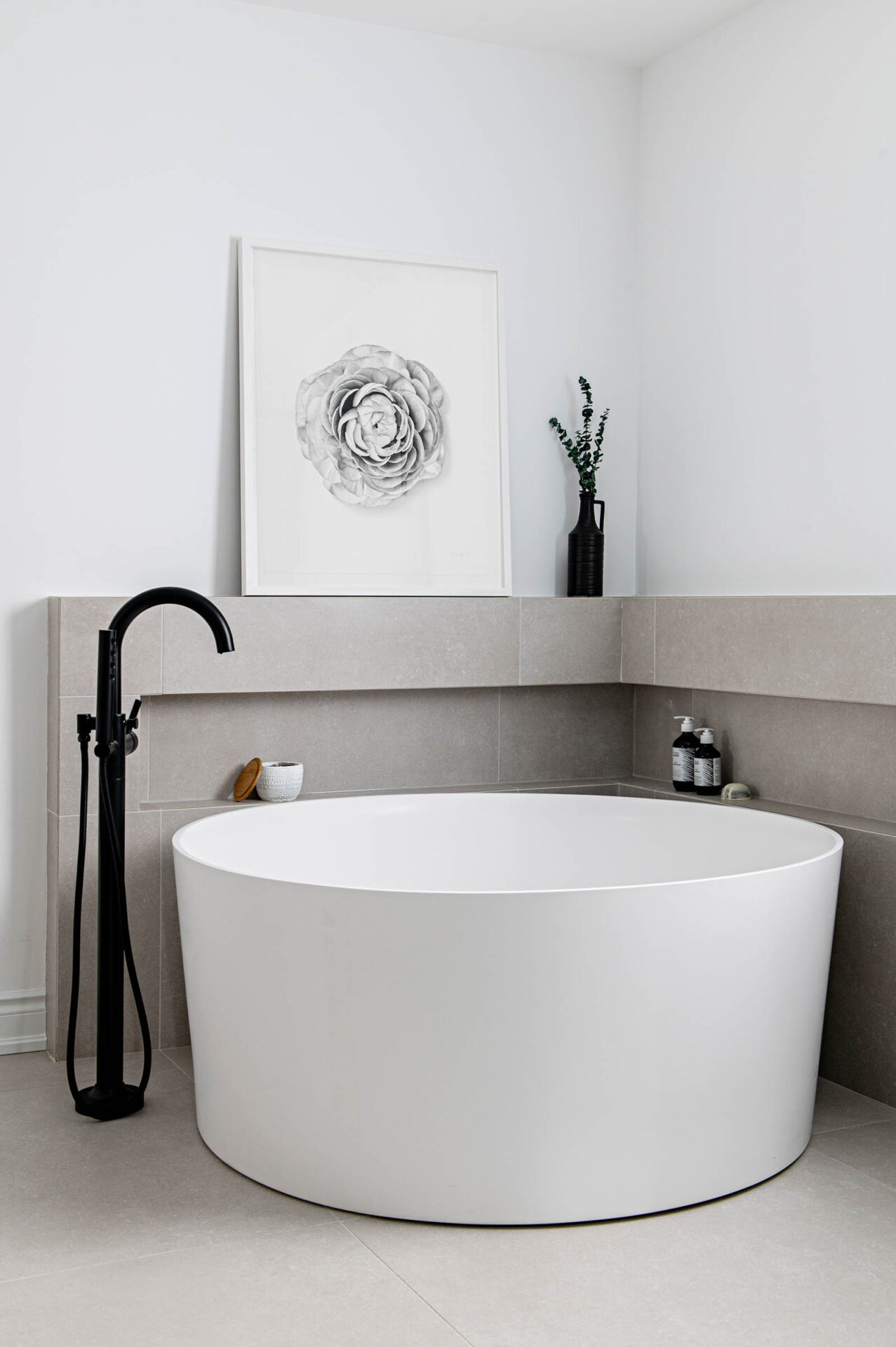 Image of contemporary primary ensuite with white round tub and black floor mount tub filler.