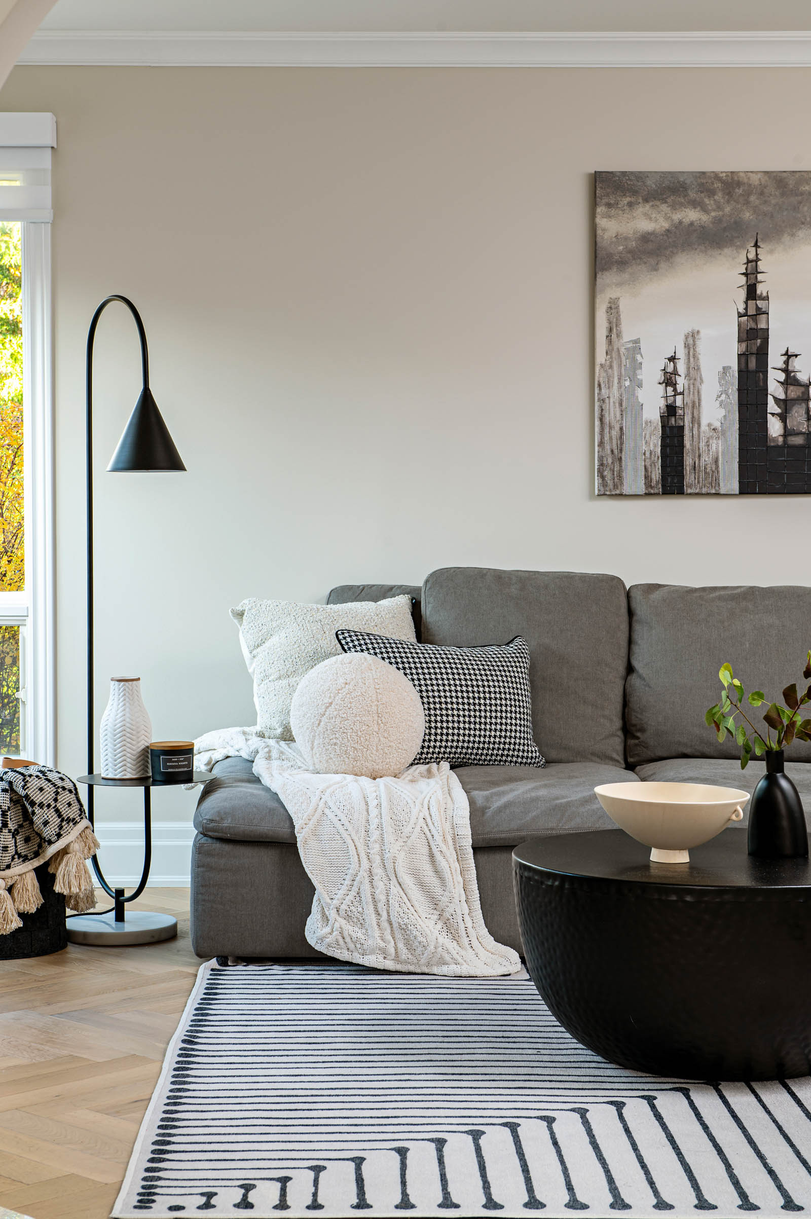 Image of a cozy modern family room decor with grey sectional, black and white area rug, and black coffee table.