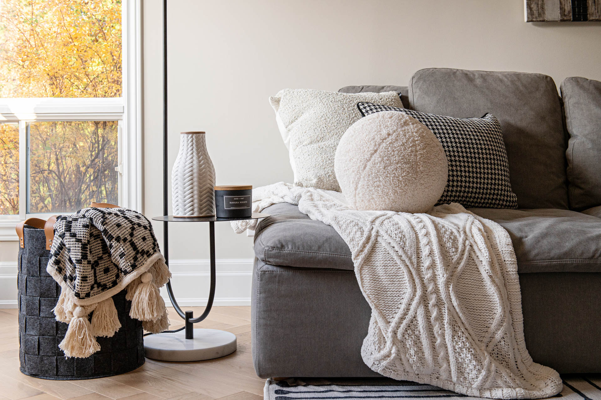 Image of Family Room grey sectional with knitted blanket, houndstooth throw pillow.