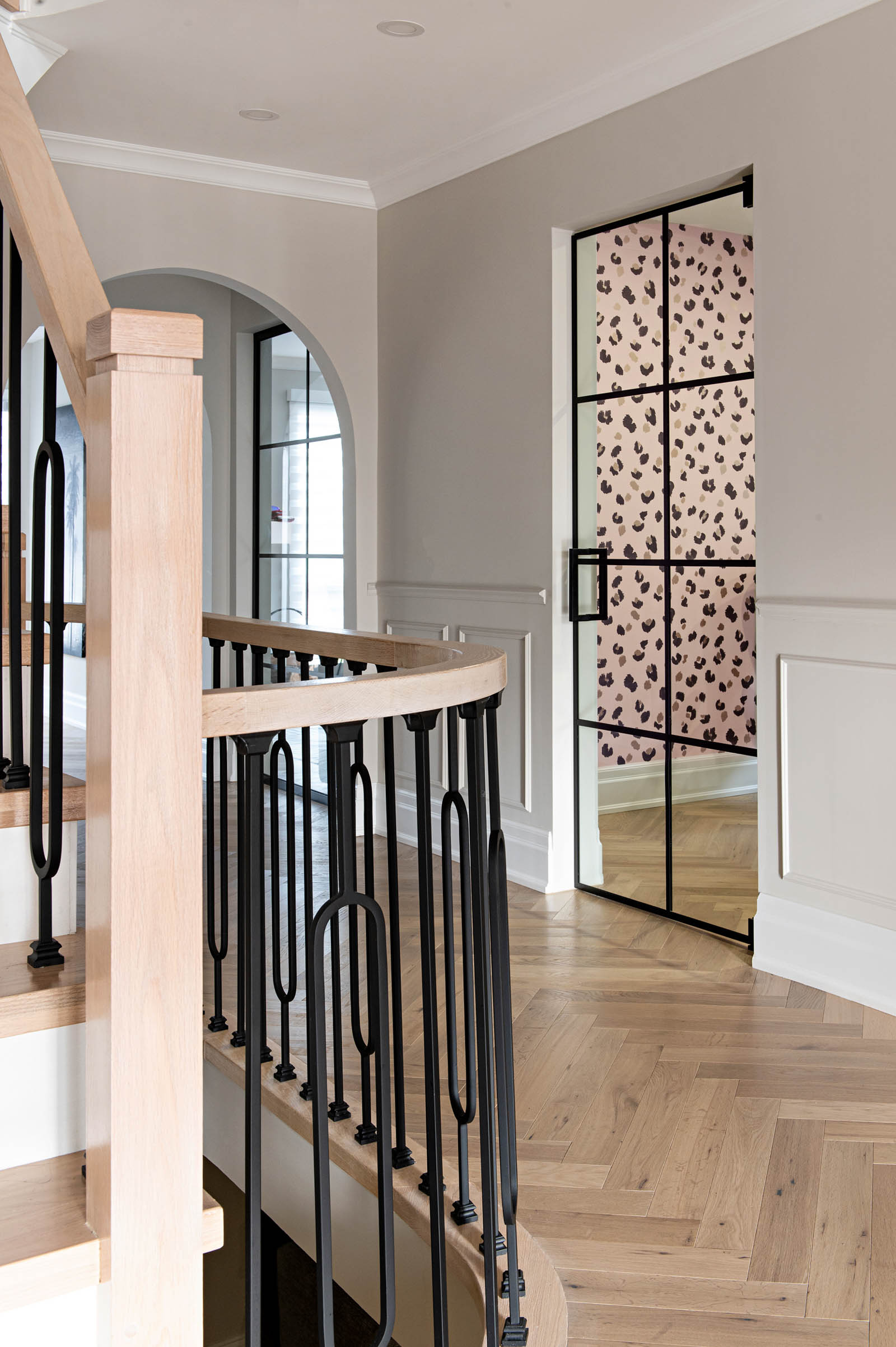 Image of an entrance hall showing a wallpaper sneak peek through the black framed glass door into Home Office Wallpaper.