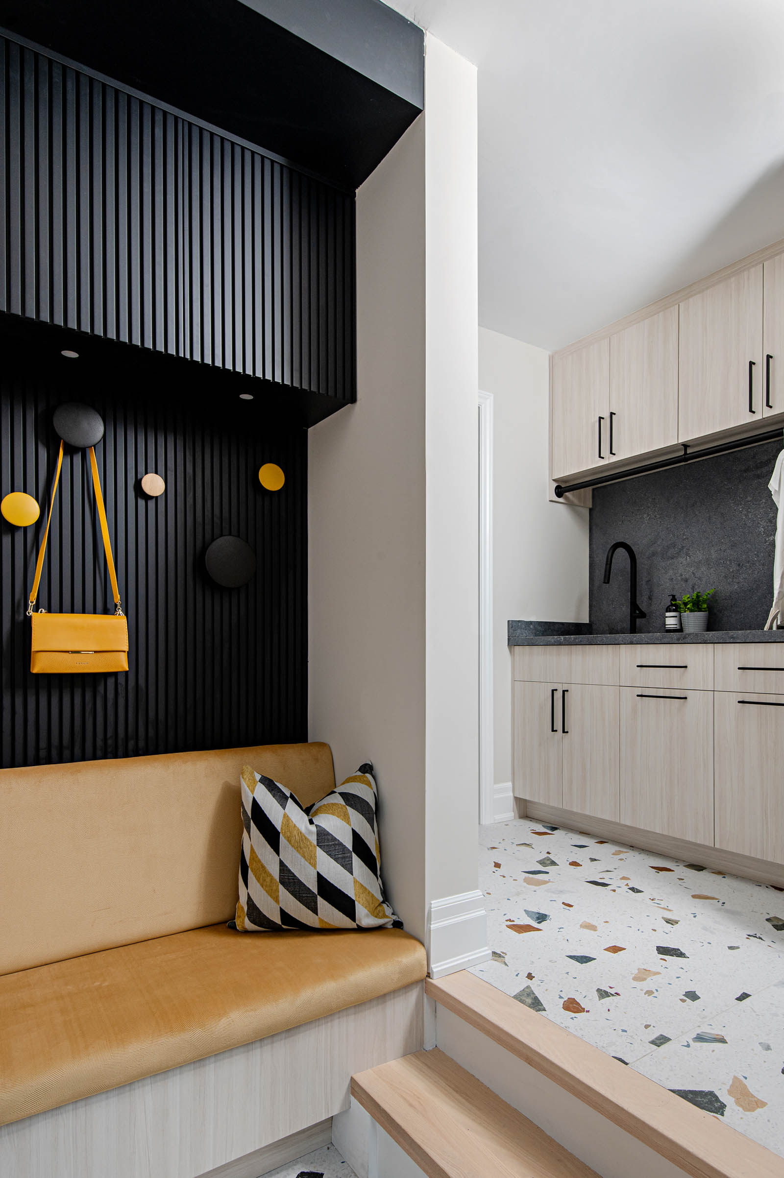 Image of modern mudroom and laundry room with porcelain colourful large scale terrazzo floor, custom laundry room cabinets and mudroom storage with bench.