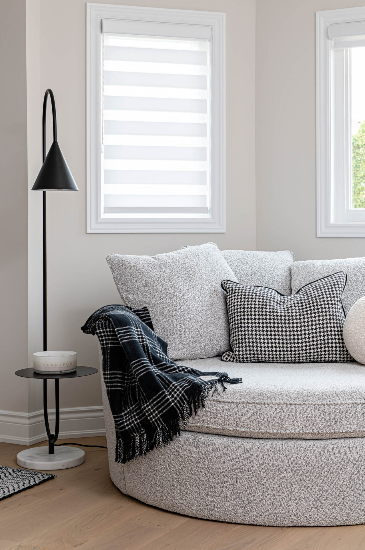 Image of cozy seating area located in the primary bedroom with a large round snuggle chair and modern black side table lamp.