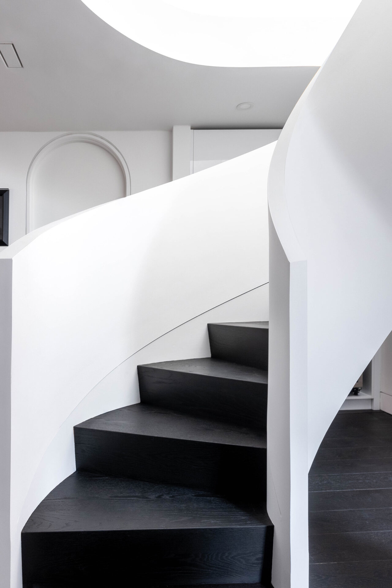 Modern curved staircase with stained black steps and white walls.
Vellore Village home transformation: modern curved staircase Vellore Village home black hardwood and white railing.